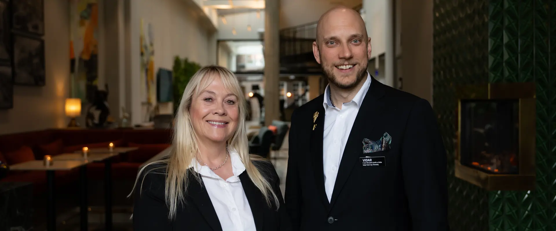 To blide hotellansatte i resepsjonen
